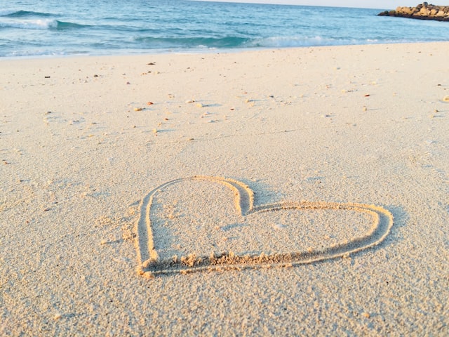 alt= "large heart drawn in the sand at a beach to represent compassion"