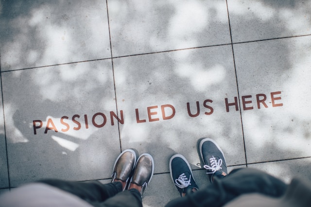 alt= "the words passion led us here and two pairs of feet on a sidewalk to indicate embracing the evolution of life purpose"
